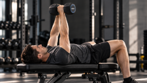 Athlete performing a dumbbell hex press on a flat bench with two black rubber hex dumbbells pressed together.